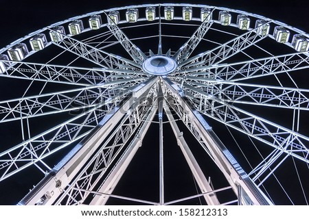 A giant wheel attraction in a park in Paris by night.