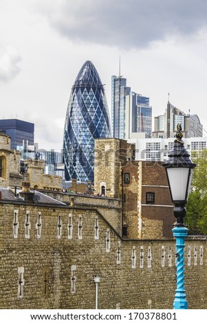 LONDON, UK - JUNE 3, 2013: View of Gherkin building (30 St Mary Axe) and Tower of London Walls - historic castle on north bank of River Thames. Gherkin skyscraper - iconic symbol of London.