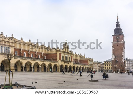 KRAKOW, POLAND - MARCH 5, 2014: Unidentified tourists taking a walk at Main Square (Rynek Glowny) with Sukiennice. Rynek Glowny - roughly 40,000 m2 is largest medieval town square in Europe.
