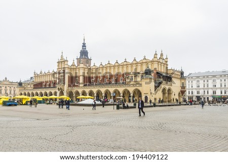 KRAKOW, POLAND - MARCH 5, 2014: Unidentified tourists taking a walk at Main Square (Rynek Glowny). It dates to the 13th century, and at roughly 40,000 m2 - largest medieval town square in Europe.