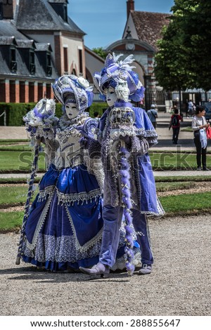 CHEVERNY, FRANCE - JUNE 10, 2015: Venetian carnival (costume party) enthusiasts, dressed in colorful costumes, masks and feathers, have animated the field of Cheverny.