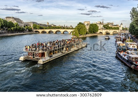 PARIS, FRANCE - JUNE 1, 2015: View of the Seine River with cruise tour boats. In Paris there are several boat tourist trips across the Seine to show tourists the sights of interest.