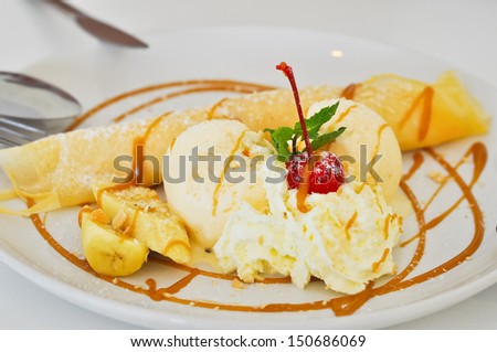 Vanilla ice cream and crepes stuffed with bananas topped with caramel and whipped cream.