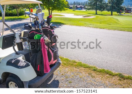 Golf Club Bags on back of cart. Golf course with sand trap in background. Copy space.