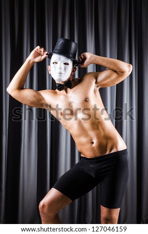 Muscular actor with mask against curtain