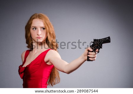 Pretty young girl in red dress with gun isolated on white