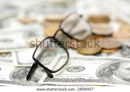 Reading glasses with coins  and dollar bank notes