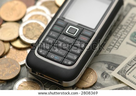 Mobile phone with coins  and dollar bank notes