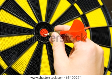 Male hand throwing dart arrow in bulls eye on dart board game