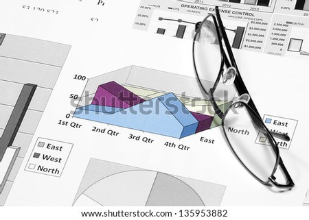 business financial chart analysis with eyeglasses on paper work
