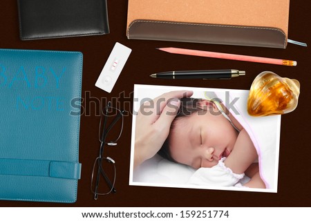 baby photo with paperweight & pregnancy test on the desk
