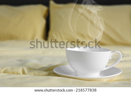 hot coffee and smoke in white cup on yellow bed