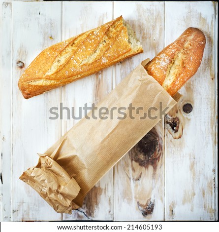 Loaf of bread in a grocey paper bag (european style) on a rustic table.