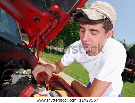 A smiling teenage boy working on a truck engine.