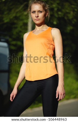 Young attractive female in orange fitness outfit