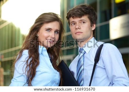 Close portrait of a smiling attractive business young couple with briefcase, background