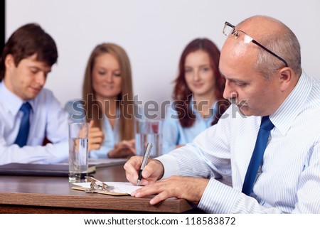 Senior businesswoman sitting on a business meeting with younger colleagues, background in the office