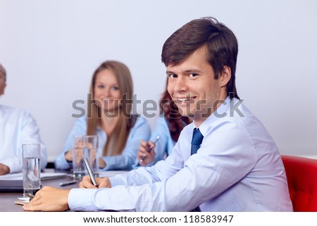 Young smiling attractive businesswoman sitting on a business meeting with colleagues, background in the office