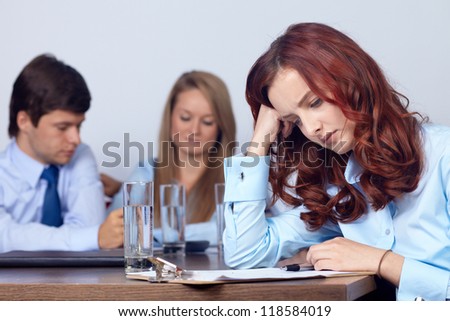 Tired unhappy young attractive businesswoman on a business meeting, background in the office