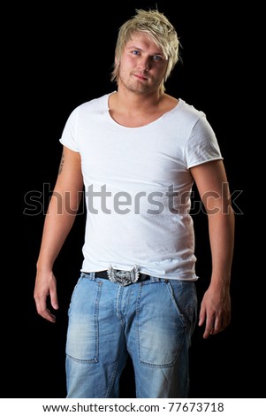 young attractive blonde male in white tshirt and jeans trousers isolated on black background