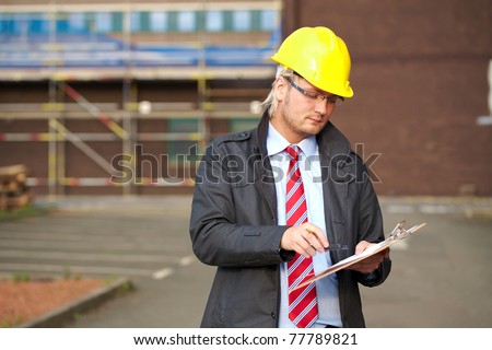 young architect or inspector with office building as blurred background