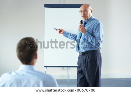 senior manager during seminar, presentation, point to white board and hold microphone, indoor shoot