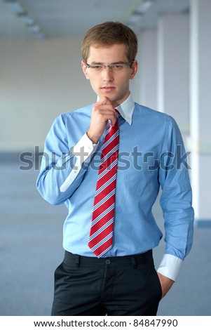 Young thoughtful businessman in blue shirt and red tie, office shoot