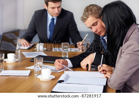 Team of 3 business people working on some calculations, calculator and some documents on table