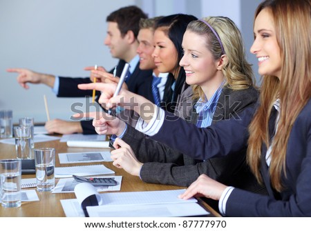 Team of 5 business people sitting at conference table point forward with their fingers,