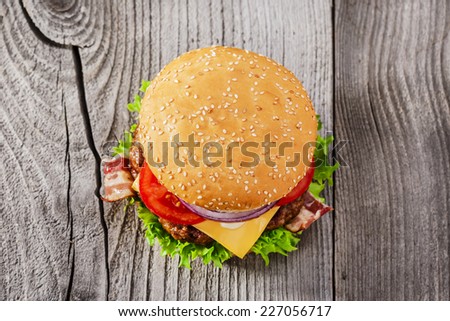 hamburger with grilled meat cheese bacon on a wooden surface