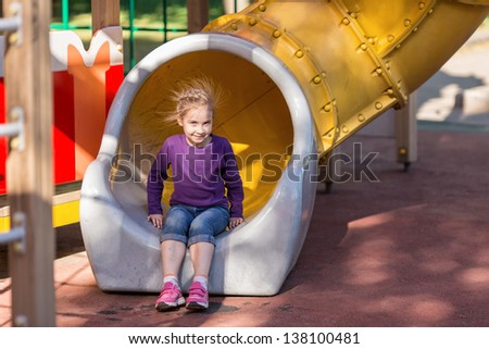 Beautiful little girl on outdoor playground at summertime