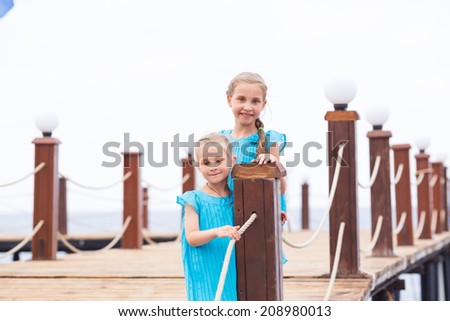 Portrait of beautiful little girls, sisters on the pier at the seaside