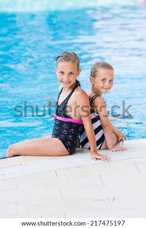 Two cute little girls in swimming pool posing