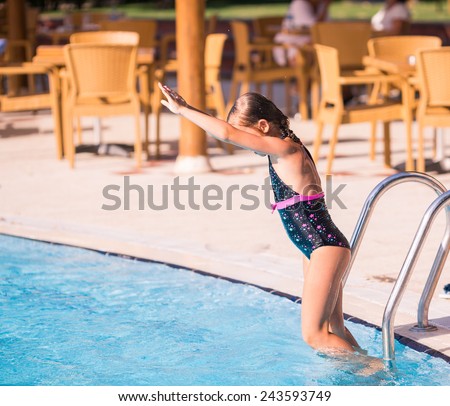 Cute little girl is ready to jump into swimming pool learning how to swim