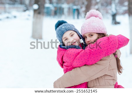 Happy girls playing on snow in winter time
