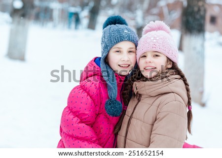 Happy girls playing on snow in winter time