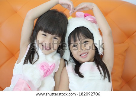Two lovely girl use hand cover and touch to make heart sign together in studio