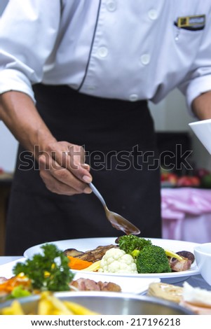 Chef apply chicken soup to vetgetable and steak food in restaurant
