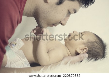 Dad and son play ,kiss ,and cover baby on the bed