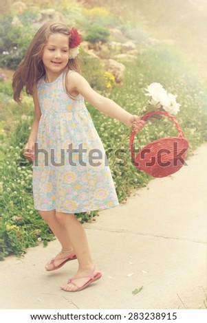 Happy little girl with flowers, dancing, having fun, enjoying in summer garden . Fine art image