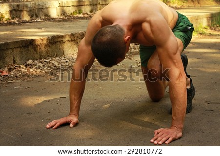 Young muscular attractive man in low start position preparing for sprint.