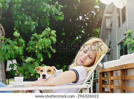 Young beautiful woman drinking a coffee sitting outside in a Rustic Chic cafe with her dog jack russell terrier