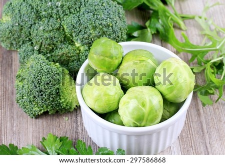 Brussels sprouts, broccoli and rucola, fresh vegetables on wooden background