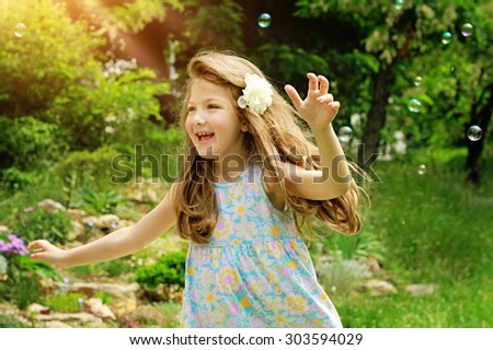 Fine art summer portrait of beautiful girl playing outside with soap bubbles. Child outside, ruining. Freedom concept