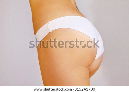 Fitness girl, closeup of young female a back, trained buttocks, slim tanned woman\'s body on white background.