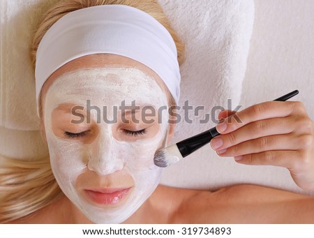 Young beautiful girl applying homemade facial mask i at home.Skin care, beauty treatments.