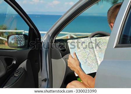 Man siting in  the car and looking at road map. Traveler searching right direction on map. Tourism, active lifestyle concept