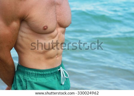 Strong muscular man on the beach, close on stomach and chest, six pack , abs. Active summer vacation