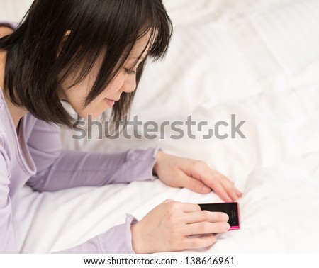 Young Asian woman using smart phone on the bed