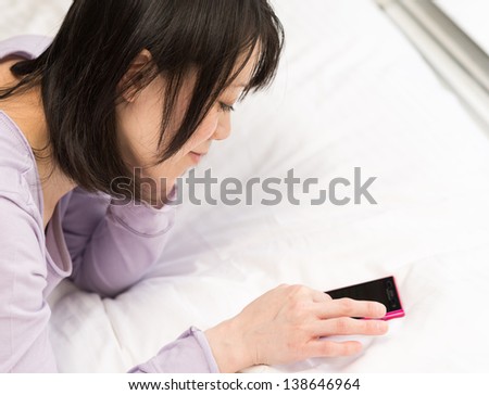 Young Asian woman using smart phone on the bed